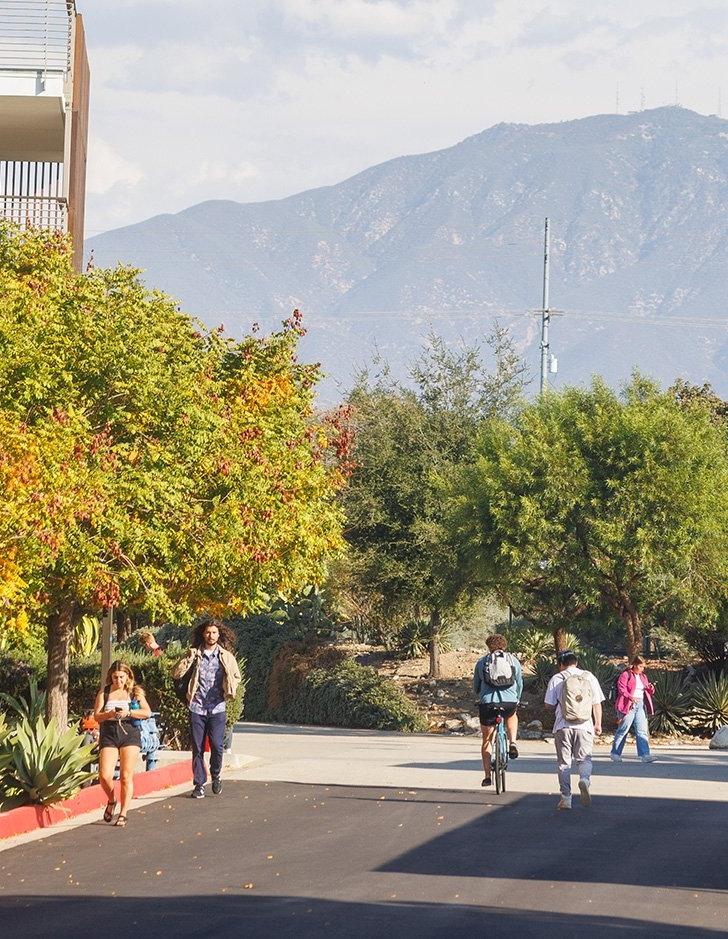 several students walk down pitzer road with the san bernardino mountains in the background